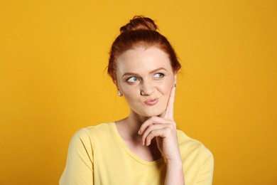 Photo of Portrait of thoughtful red haired woman on yellow background
