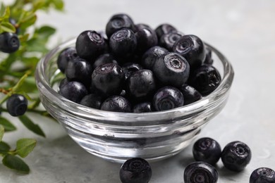 Photo of Ripe bilberries in bowl on light marble table, closeup