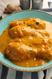 Photo of Tasty chicken curry and ginger on wooden table, closeup