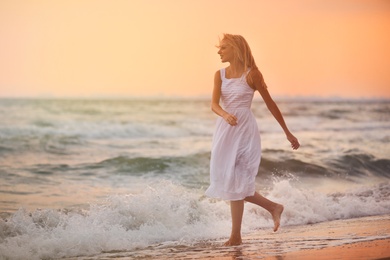 Photo of Beautiful young woman on beach at sunset