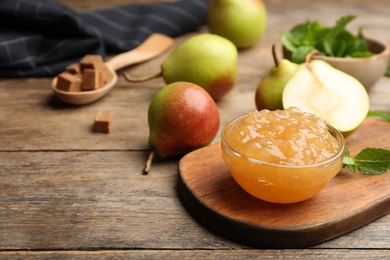 Photo of Delicious pear jam and fresh fruits on wooden table. Space for text
