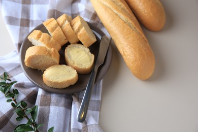 Photo of Whole and cut baguettes with fresh butter on table