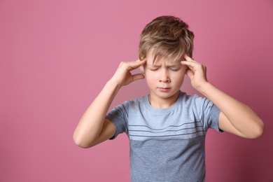 Photo of Little boy suffering from headache on color background