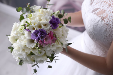 Photo of Bride holding beautiful bouquet with spring freesia flowers, closeup