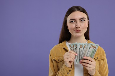 Photo of Woman with dollar banknotes on purple background, space for text