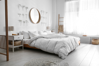 Modern bedroom interior with stylish round mirror