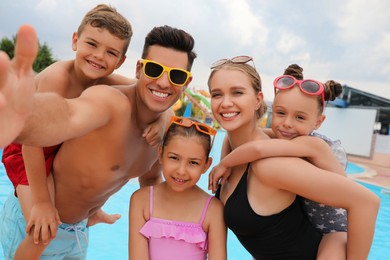 Photo of Happy family taking selfie near pool in water park