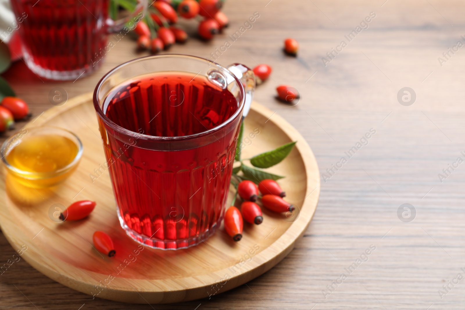 Photo of Fresh rose hip tea, honey and berries on wooden table. Space for text