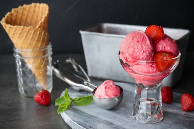 Photo of Delicious strawberry ice cream in dessert bowl served on grey table