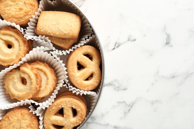 Photo of Tin box with Danish butter cookies on marble table, top view. Space for text