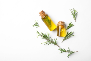 Photo of Bottles of rosemary oil and fresh twigs on white background, top view