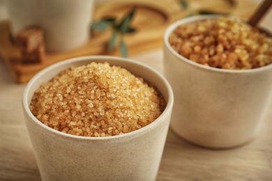 Photo of Brown sugar in bowl on wooden table, closeup