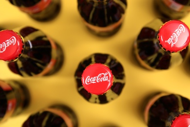 Photo of MYKOLAIV, UKRAINE - NOVEMBER 14, 2018: Bottles of Coca-Cola on color background, top view