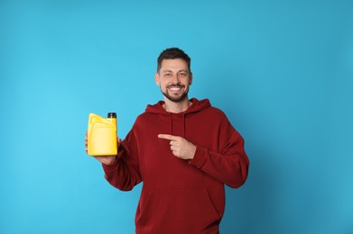 Photo of Man pointing at yellow container of motor oil on light blue background