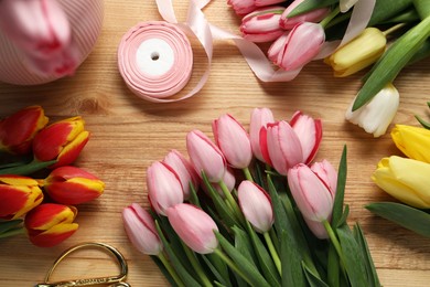 Photo of Making beautiful bouquet. Fresh tulips, ribbon and scissors on wooden table, flat lay