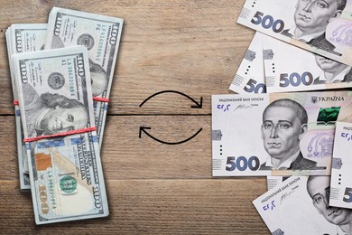Currency exchange. Circle arrows between American dollars and Ukrainian hryvnias on wooden background, flat lay