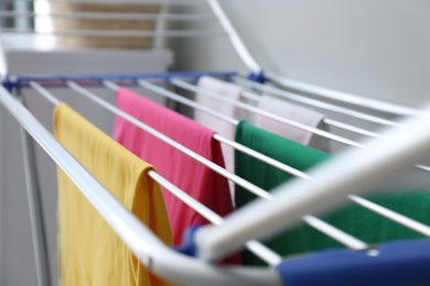 Clean laundry hanging on drying rack indoors, closeup