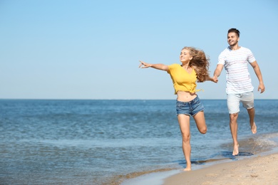 Photo of Happy young couple walking at beach on sunny day