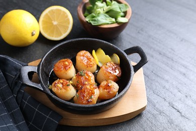 Delicious fried scallops, lemons and corn salad on dark gray textured table