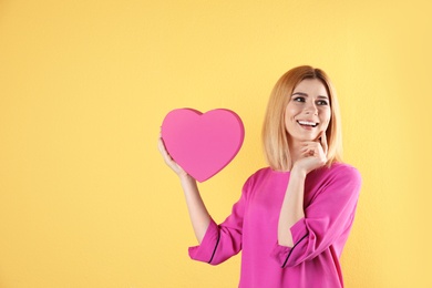 Photo of Beautiful woman with heart shaped box on color background. Space for text