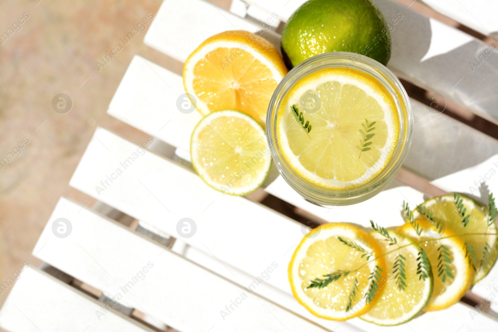 Photo of Delicious refreshing lemonade and slices of citrus on white wooden table outdoors, flat lay. Space for text