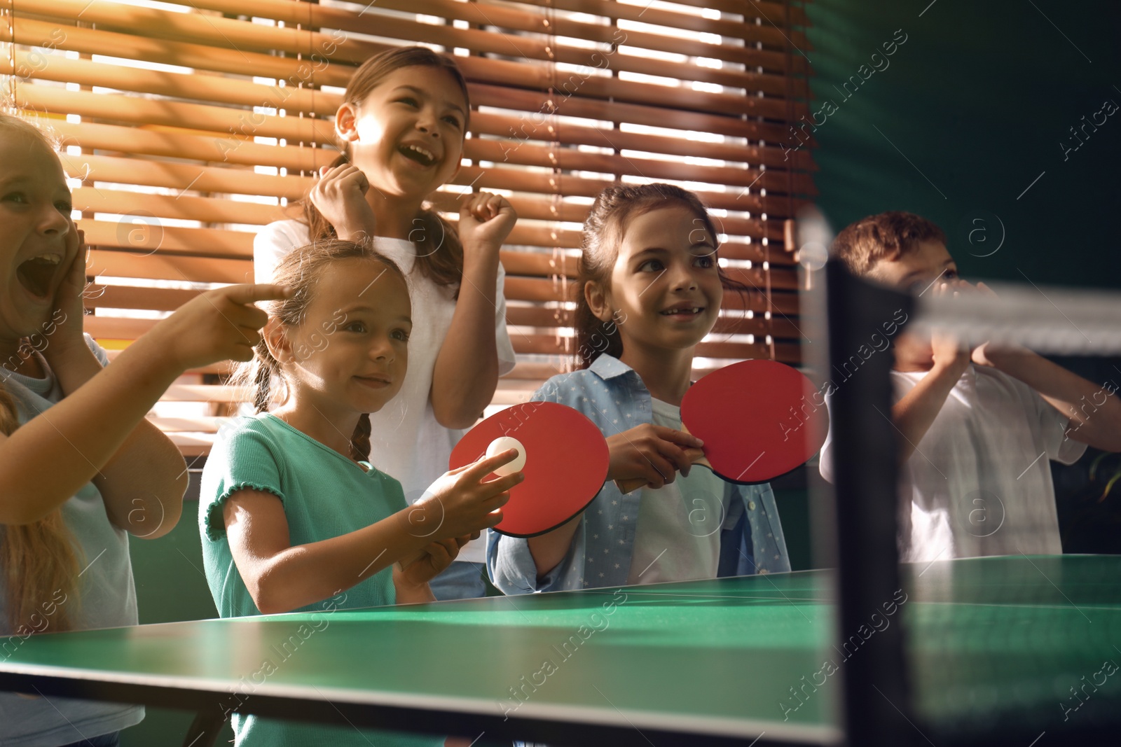 Photo of Cute happy children playing ping pong indoors