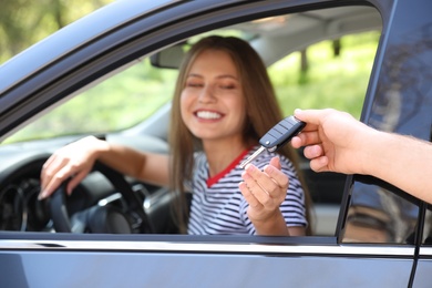 Salesperson giving car key to customer outdoors