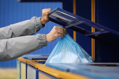 Man throwing garbage into bin at recycling point outdoors, closeup