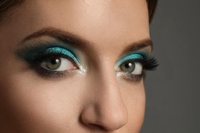 Photo of Young woman with evening makeup on grey background, closeup. Eye shadow product