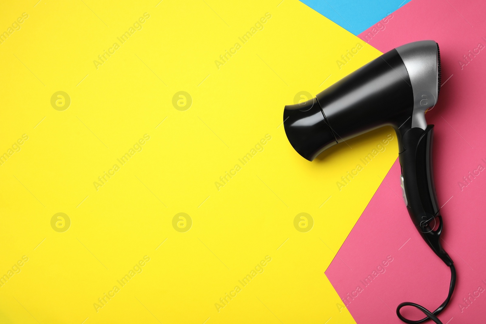 Photo of Hair dryer on color background, top view with space for text. Professional hairdresser tool