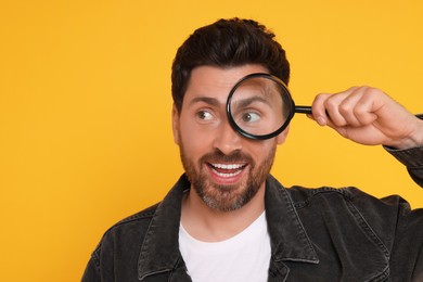 Photo of Man looking through magnifier glass on yellow background, space for text