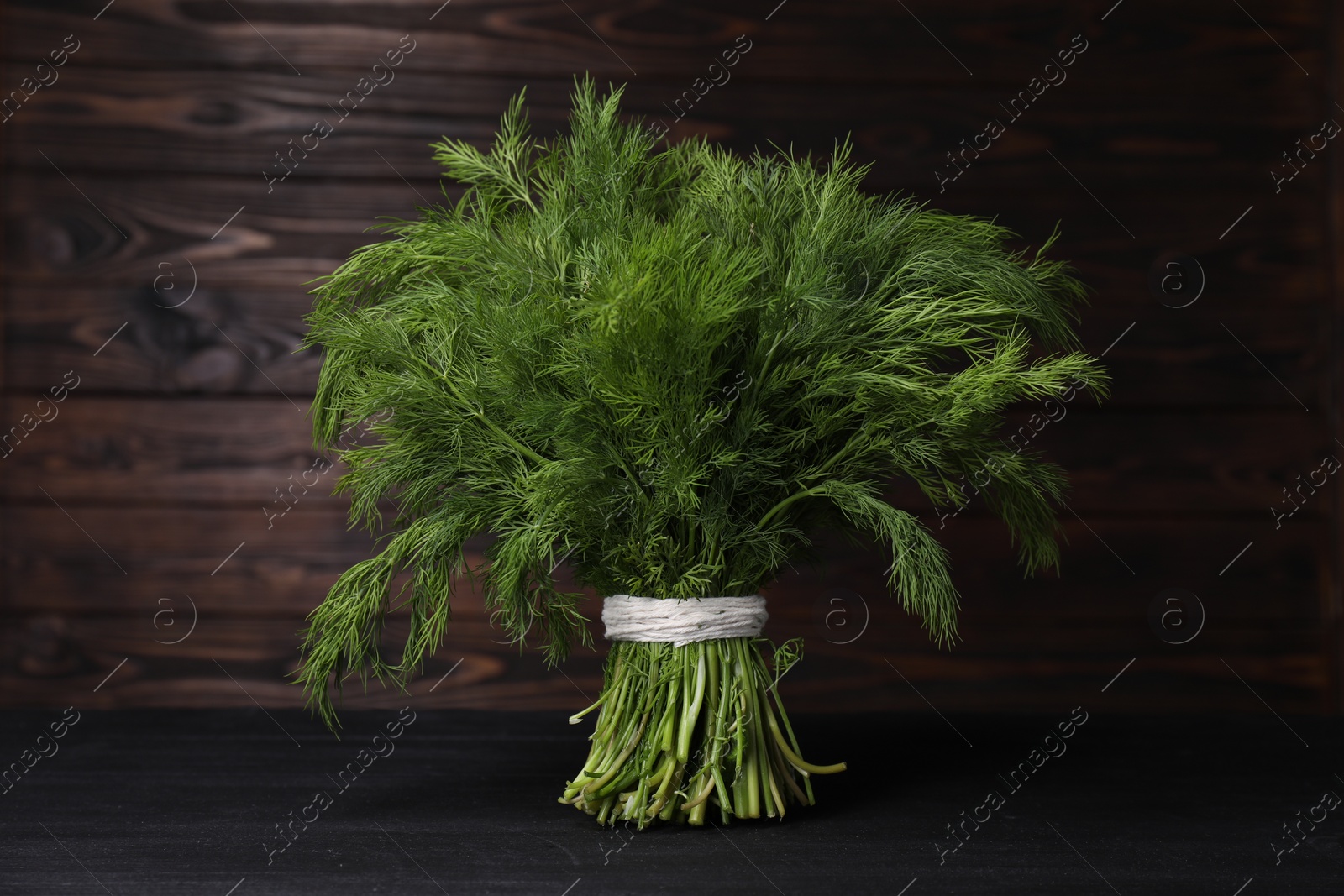 Photo of Bunch of fresh green dill on black wooden table