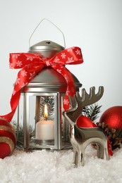 Beautiful composition with vintage Christmas lantern and festive decorations on snow against white background