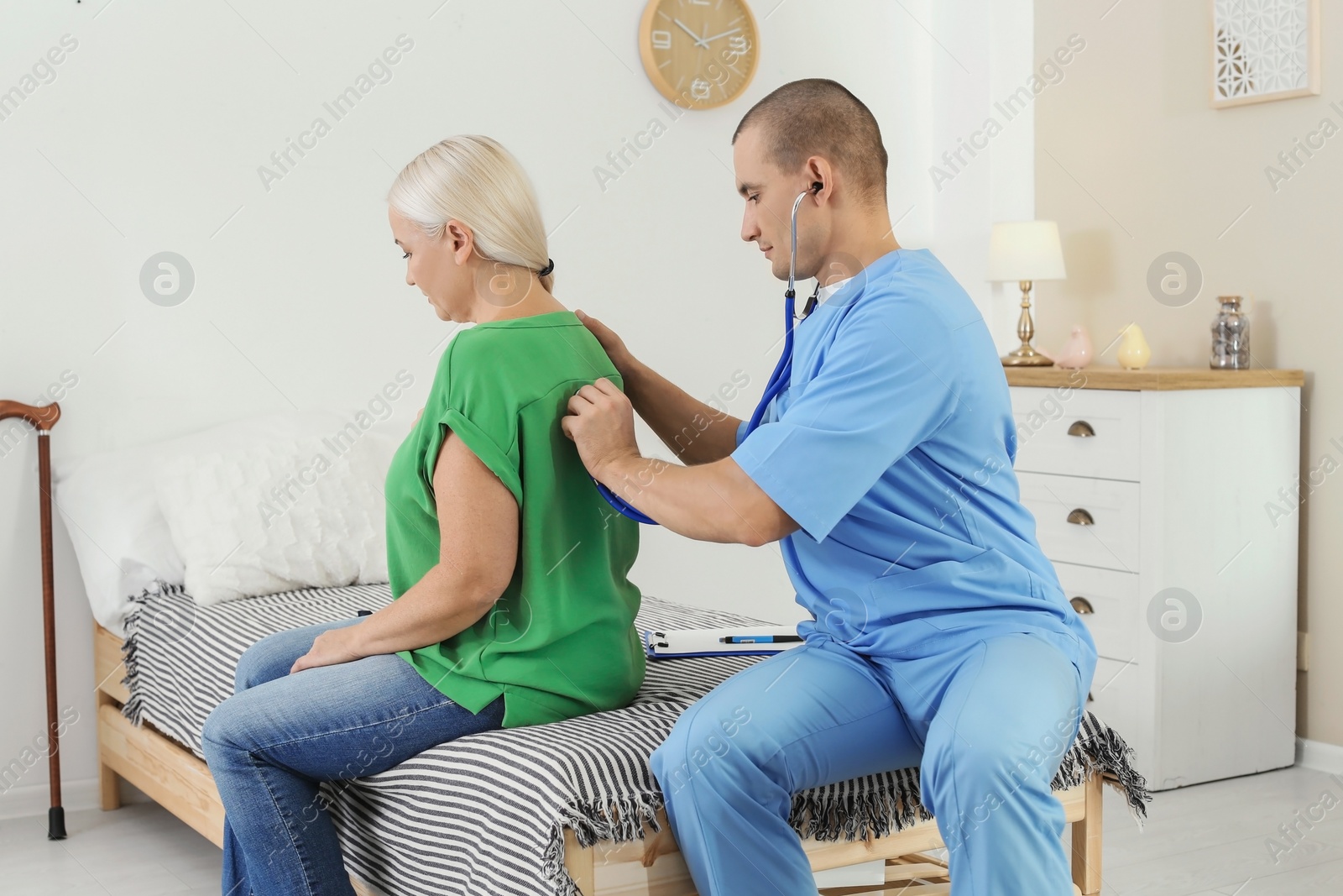 Photo of Male medical assistant examining female patient during home visit