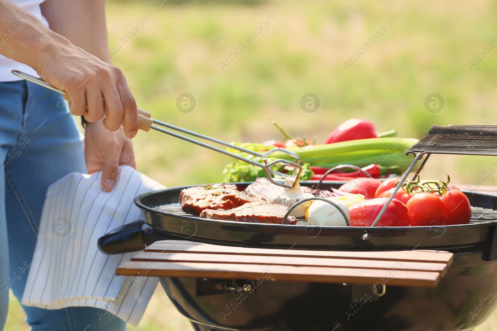 Photo of Man cooking meat and vegetables on barbecue grill outdoors