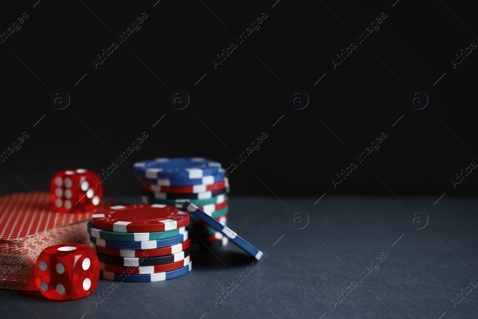 Photo of Poker chips, cards and dices on dark background, space for text