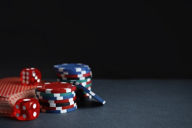 Photo of Poker chips, cards and dices on dark background, space for text