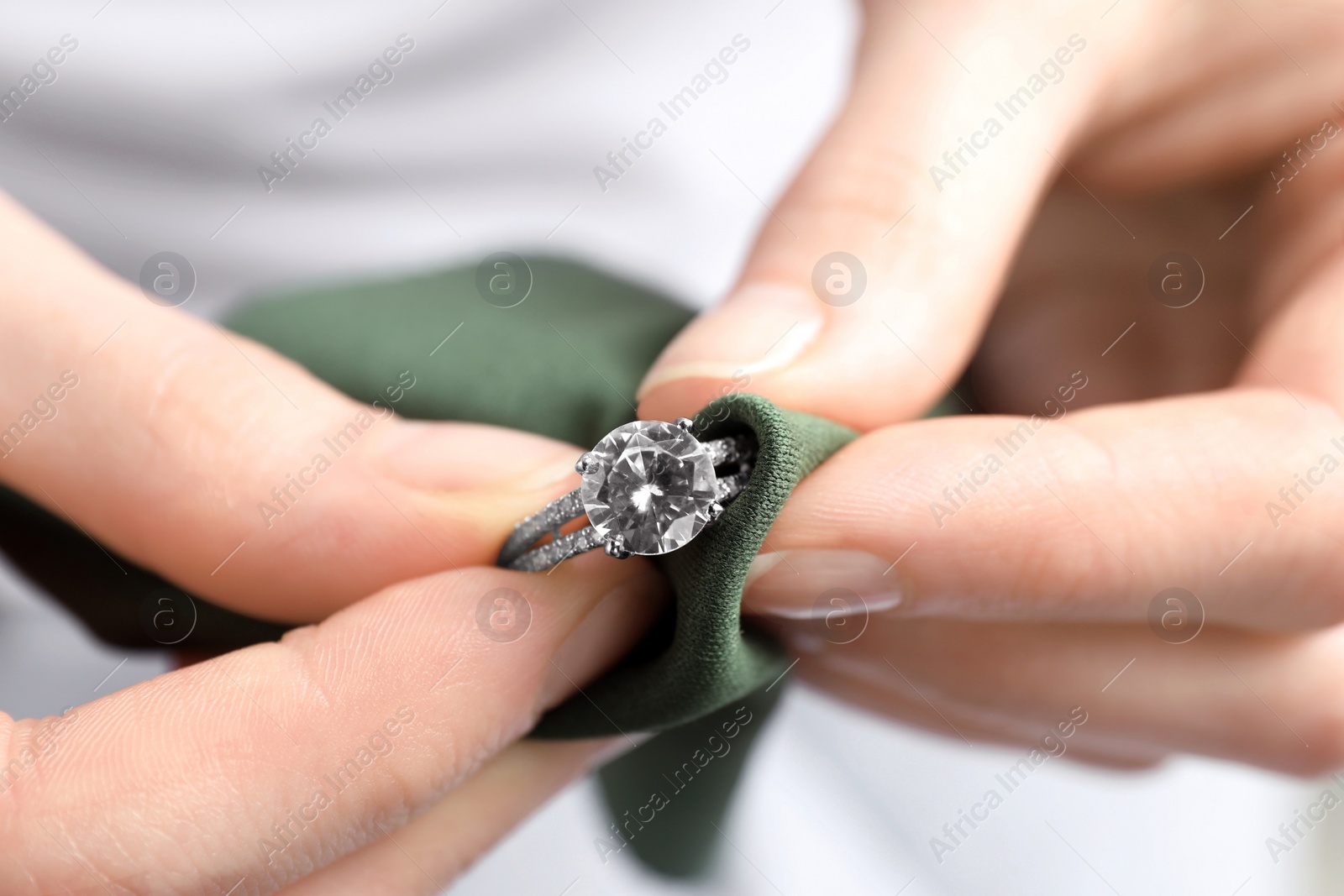 Photo of Jeweler cleaning diamond ring with microfiber cloth, closeup