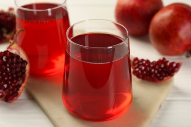 Photo of Tasty pomegranate juice in glasses and fresh fruits on white wooden table, closeup