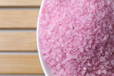 Photo of Bowl with pink sea salt on wooden table, top view