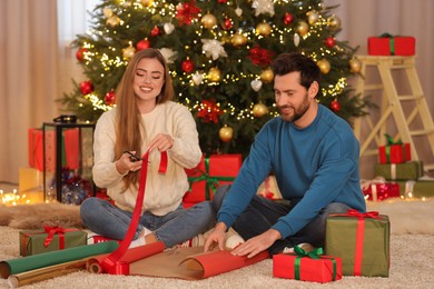 Photo of Happy couple decorating Christmas gift at home