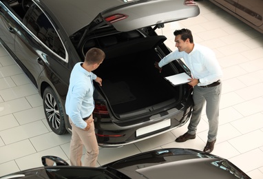 Young salesman working with client in modern car dealership, above view