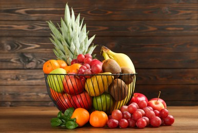 Metal bowl with different fresh fruits on wooden table