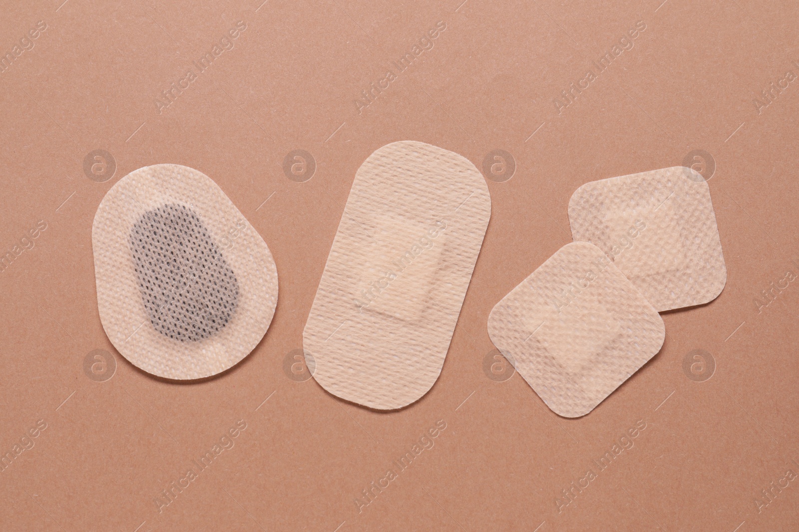 Photo of Different contraceptive patches on light brown background, flat lay