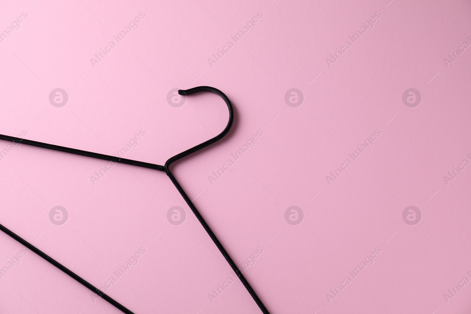 Photo of One black hanger on pink background, top view. Space for text