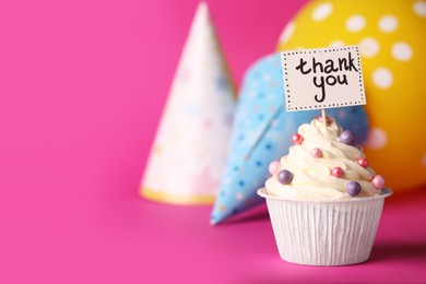Photo of Tasty cupcake with Thank You note and paper cones on pink background, space for text