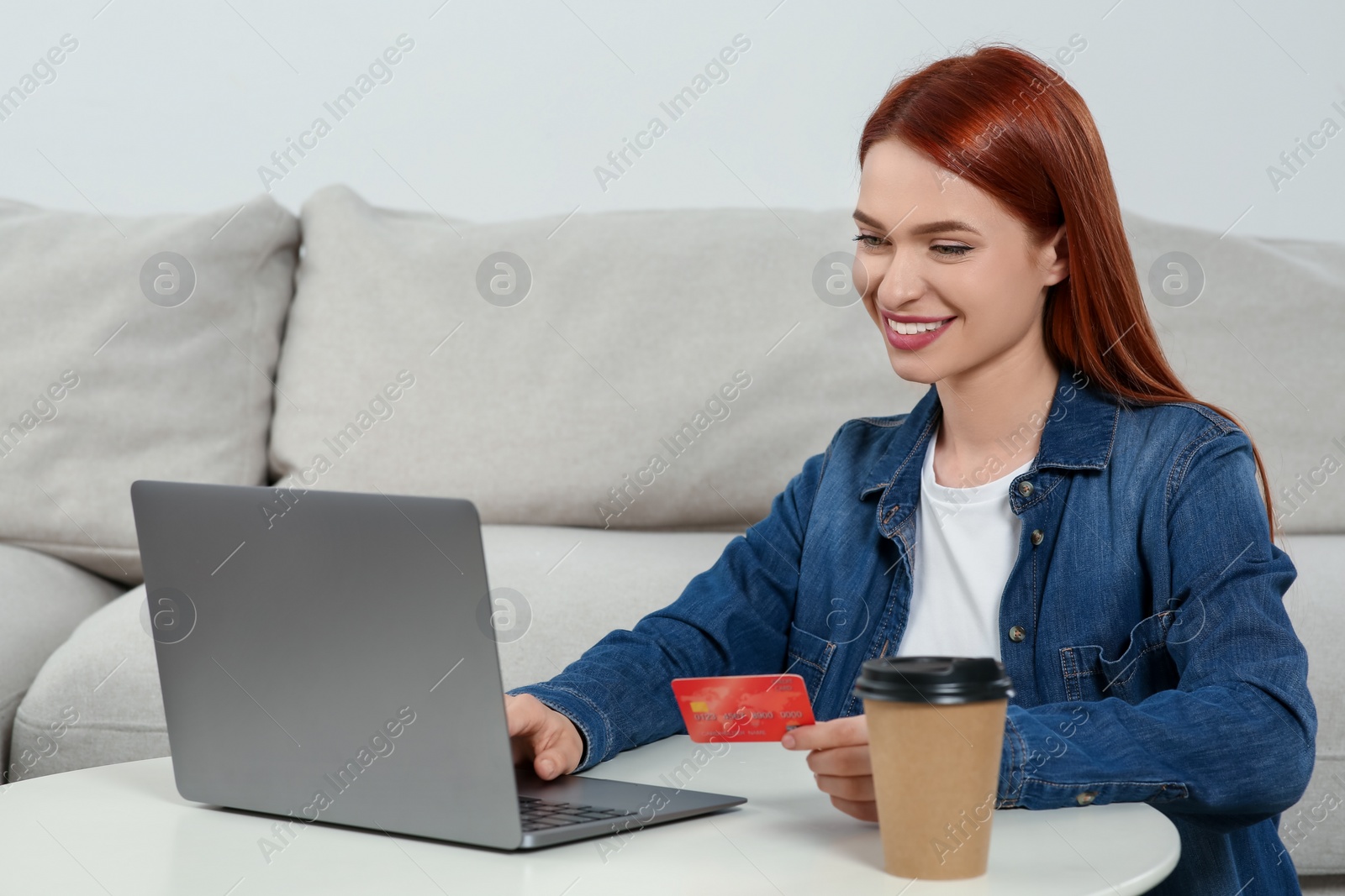 Photo of Happy woman with credit card using laptop for online shopping at home