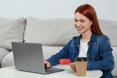 Happy woman with credit card using laptop for online shopping at home