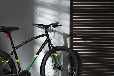 Modern black bicycle near grey wall indoors