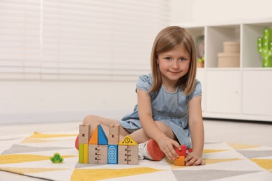 Photo of Cute little girl playing with wooden toys indoors, space for text